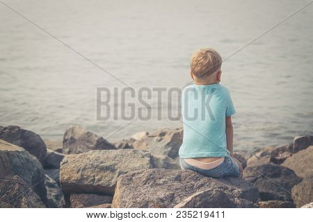 Cute caucasian boy at seaside. Rear view. Leisure time