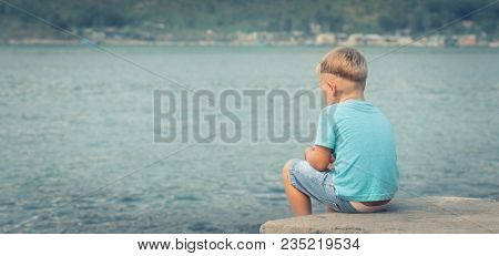 Cute caucasian boy at seaside. Rear view. Leisure time