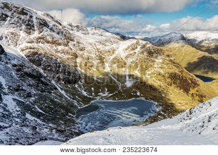 Looking Down On Frozen Low Water, A Tarn In The English Lake District Below The Old Man Of Coniston.