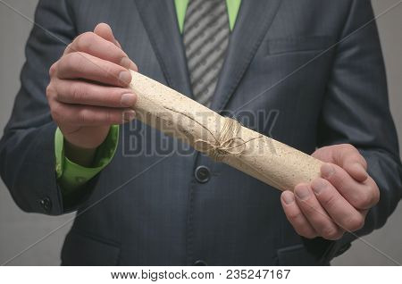 Businessman Holds In Hand A Rolled Up Document Scroll. Signing Of An Agreement. Conclusion Of A Busi