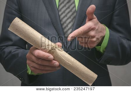 Businessman Holds In Hand A Rolled Up Document Scroll. Signing Of An Agreement. Conclusion Of A Busi