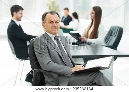 Senior Businessman With A Clipboard On The Background Of The Office.photo With Copy Space