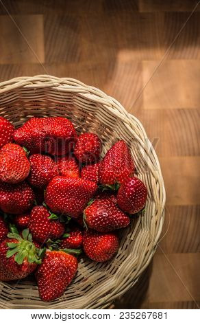The Red Ripe Strawberries In Wicker Basket On Wooden Desk.
