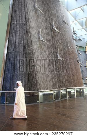 Dubai, Uae - November 22, 2017: Shopper Walks By The Human Waterfall Art Piece At Dubai Mall. It Is 