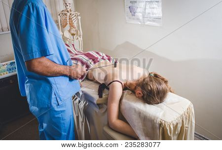 Professional Masseur During A Session Of Plantar Reflexology, Tapping With A Tiny Hammer