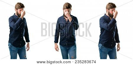 Young man with beard with sleepy expression, being overworked and tired, rubbes nose because of weariness isolated over white background