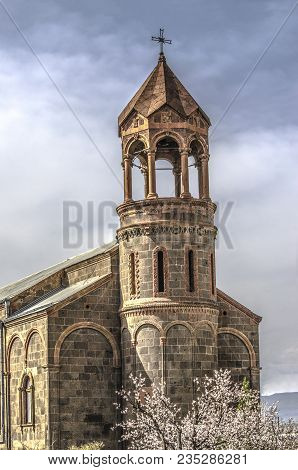 Church Of St.mesrop Mashtots With A Cylindrical Bell Tower Among Flowering Apricot Trees In The Vill