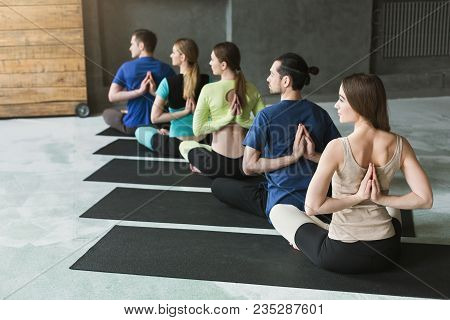 Young Women And Men In Yoga Class, Meditation Exercises. Reverse Prayer Pose, Back And Shoulders Str
