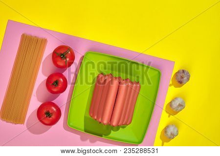 A Lot Of Raw Sausages On Plate. On Yellow Background With Pasta And Vegetables, Top View. Still Life