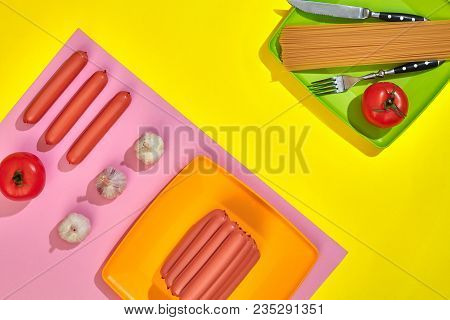 A Lot Of Raw Sausages On Plate. On Yellow Background With Pasta And Vegetables, Top View. Still Life