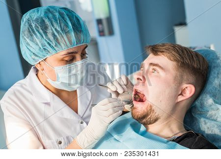 Overview Of Dental Caries Prevention. Man At The Dentist's Chair During A Dental Procedure. Healthy 