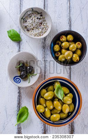 Assortment Of Olives With Herb And Sea Salt On White Wooden Background