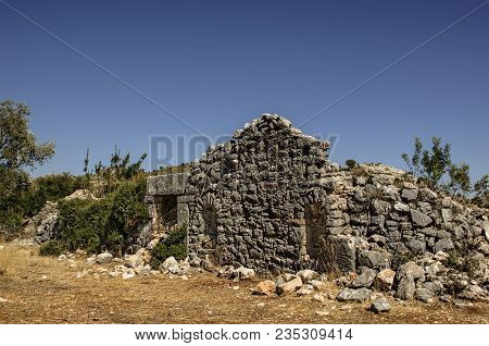 Ruins Of The Ancient City Of Sidima, Turkey, A Wall With A Partially Preserved Arch Against A Blue S