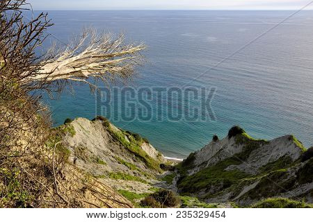 Hidden Beach Near To Kavos In Corfu Viewed From An Edge Of An Abyss With A Fallen Tree In The Front
