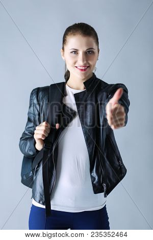 portrait of beautiful young brunette woman in stylish black jacket on gray.