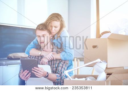 Young couple moving in new home.Sitting and relaxing after unpacking.Looking something on laptop. Young couple