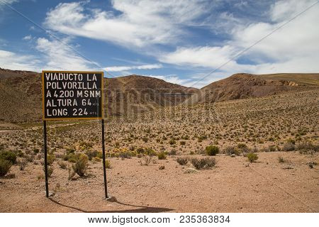 An Information Sign About The Polvorilla Viaduct Sign And Train Driving In The Background.