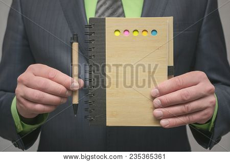 Businessman Showing In Hand A Note Pad With Copy Space With Pen. To Do List Template. Goals Or Busin