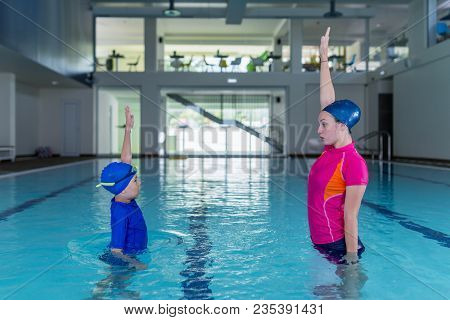 Swimming Lesson. Cute Little Boy Learning To Swim With Swimming Instructor