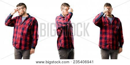 Young man with sleepy expression, being overworked and tired, rubbes nose because of weariness isolated over white background, collage composition