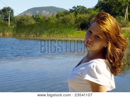La giovane ragazza uno sul lago, guarda lontano