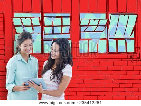 2 young women with tablet looking the new office lines. Red wall of bricks with windows
