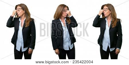 Middle age business woman with sleepy expression, being overworked and tired, rubbes nose because of weariness over white background