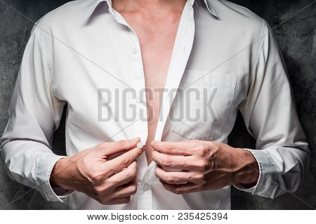 Close Up Of A Man Taking Off His White Shirt On Gray Grunge Background
