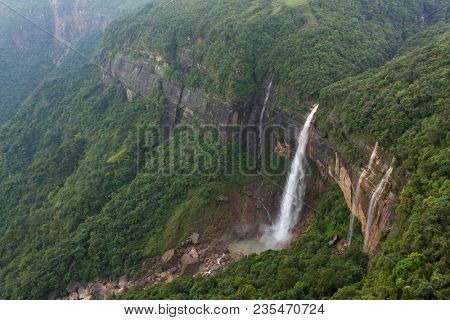 Nohkalikai waterfall surrounded by high cliffs and woodland and thick vegetation near Cherrapunji, Meghalaya, India.