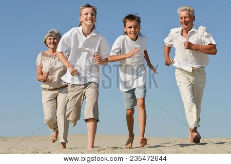 Happy Family Playing Catch-up On The Sand