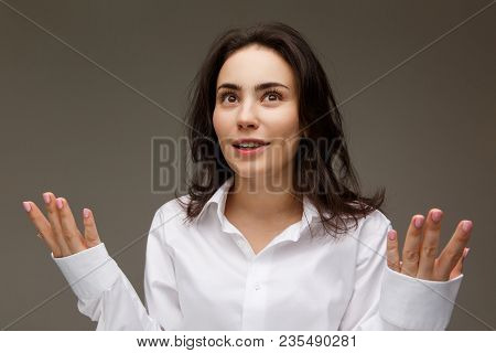 Beautiful Girl In A White Shirt Shows Emotions. On A Light Background.