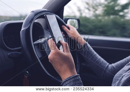 Woman Simultaneously Driving Car And Typing Text Message, Mobile Smart Phone In Female Hands Over Ve