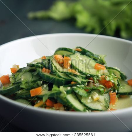 Asian Cucumber Salad On The White Plate. Chinese Cuisine. Bell Pepper, Cucumber And Sesame Seeds. Ve