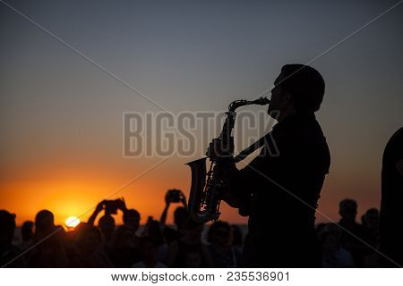 Young Man Plays Saxophone At Sunset In Front Of Public In Southern Spain
