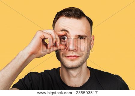 Young Man With Finger At Wide Eye, Isolated On Orange.
