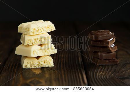 Pyramids Of Tasty White And Dark Chocolate Pieces On Wooden Dark Background In Moodle Style