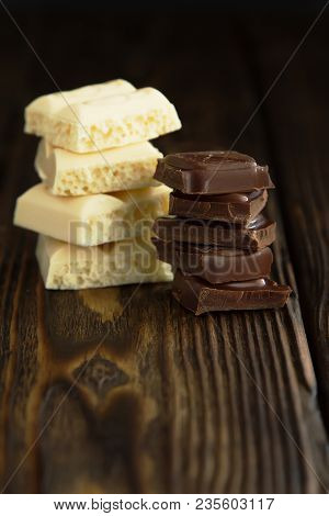Pyramids Of Tasty White And Dark Chocolate Pieces On Wooden Dark Background In Moodle Style