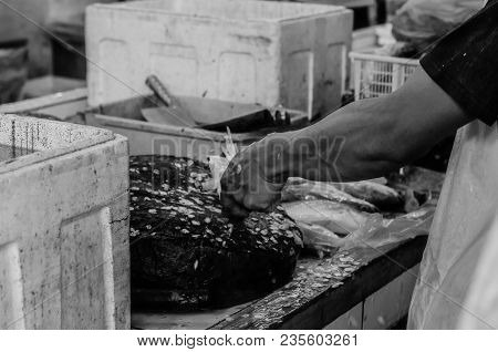 Black And White Image Of Fresh Market Scene In Malaysia, Fish Monger Clening His Fish Before Selling