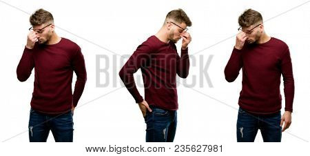 Handsome blond man with sleepy expression, being overworked and tired, rubbes nose because of weariness isolated over white background