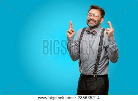 Middle age man, with beard and bow tie with crossed fingers asking for good luck