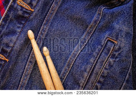Two Drumsticks Lie On A Denim Jeans Textile