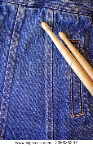 Two Drumsticks Lie On A Denim Jeans Textile