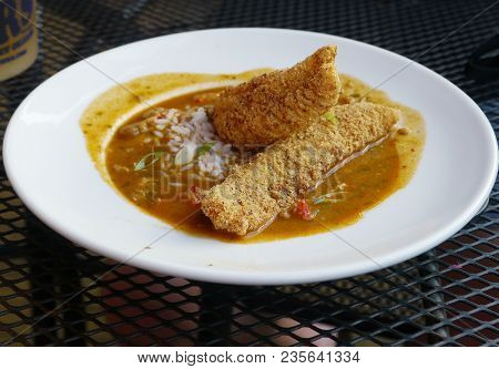 Gumbo With Deep Fried Breaded Chicken Served On A Round White Plate
One Of The Must-try Dishes When 