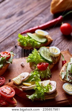 Breakfast Sandwich With Homemade Paste, Vegetables And Fresh Greenson Wooden Cutting Board Over Rust