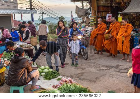 Mae Salong, Thailand - February 8, 2017: Morning street scene in Mae Salong village, Northern Thailand. Thai monks collecting alms and offerings on local market.