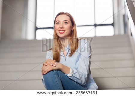 people, business and education concept - happy smiling woman or student sitting on stairs