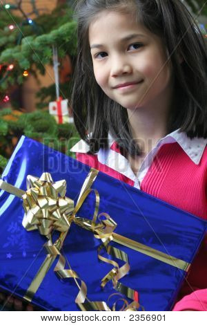 彼女のクリスマスを持って幸せな 8 歳の女の子を提示します。