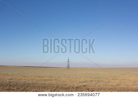 Desert Steppe With A Power Tower In The Middle Of The Field.