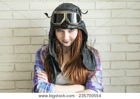 Portrait Of A Red-haired Girl In Pilot's Cap And Glasses On A Brick Wall Background