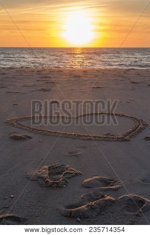 Beautiful Sunset At The Beach With Wooden Piles And Hearts Drawings In The Sand Petten, Holland, Nor